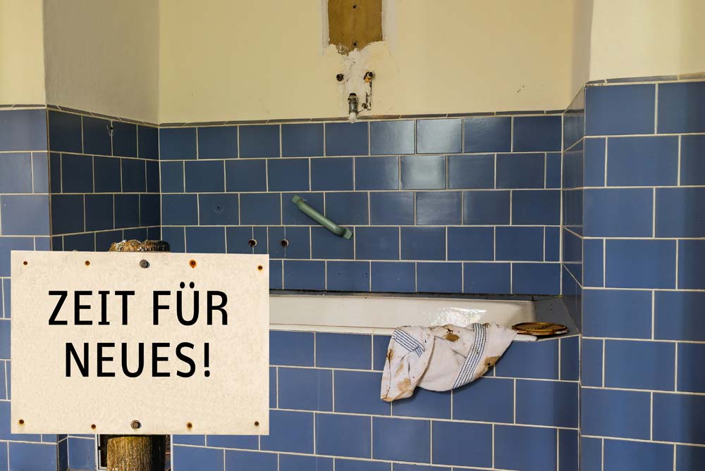 Altes Badezimmer mit blauen Fliesen und Schild: Zeit für Neues!