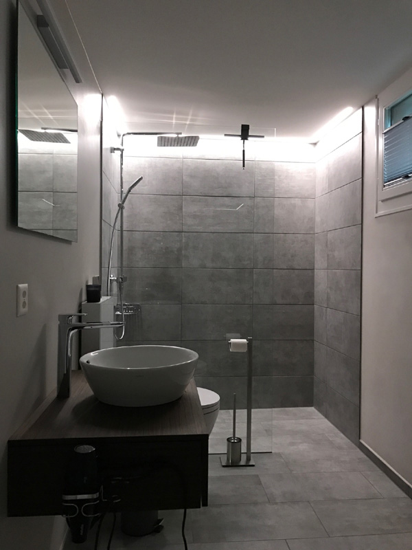 Badumbau modern mit Regenbrause, Aufsatzwaschbecken, Spiegelwand und Glasduschtrennwand